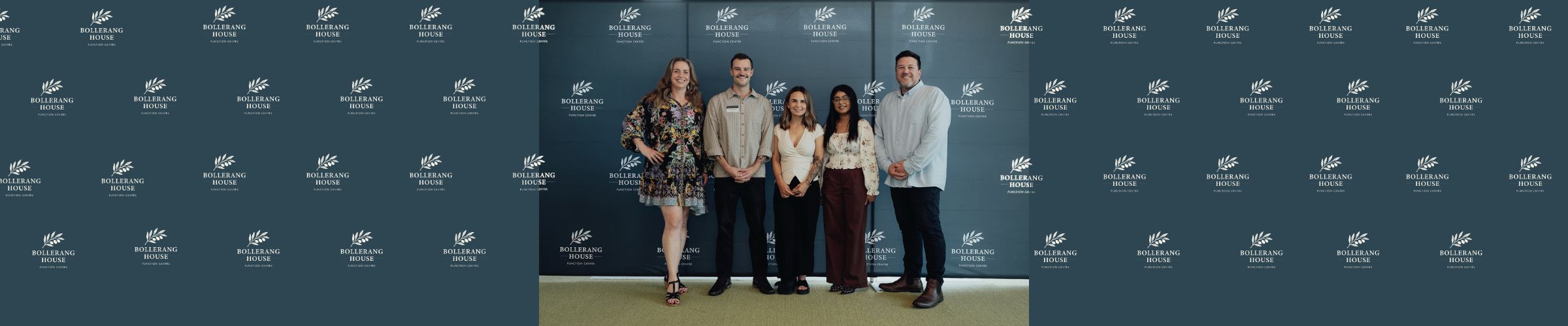 Five people stand in front of a blue backdrop with the "Walking with the Wounded" logo, smiling and posing at the Bollerang House launch celebration, dressed in business casual attire.